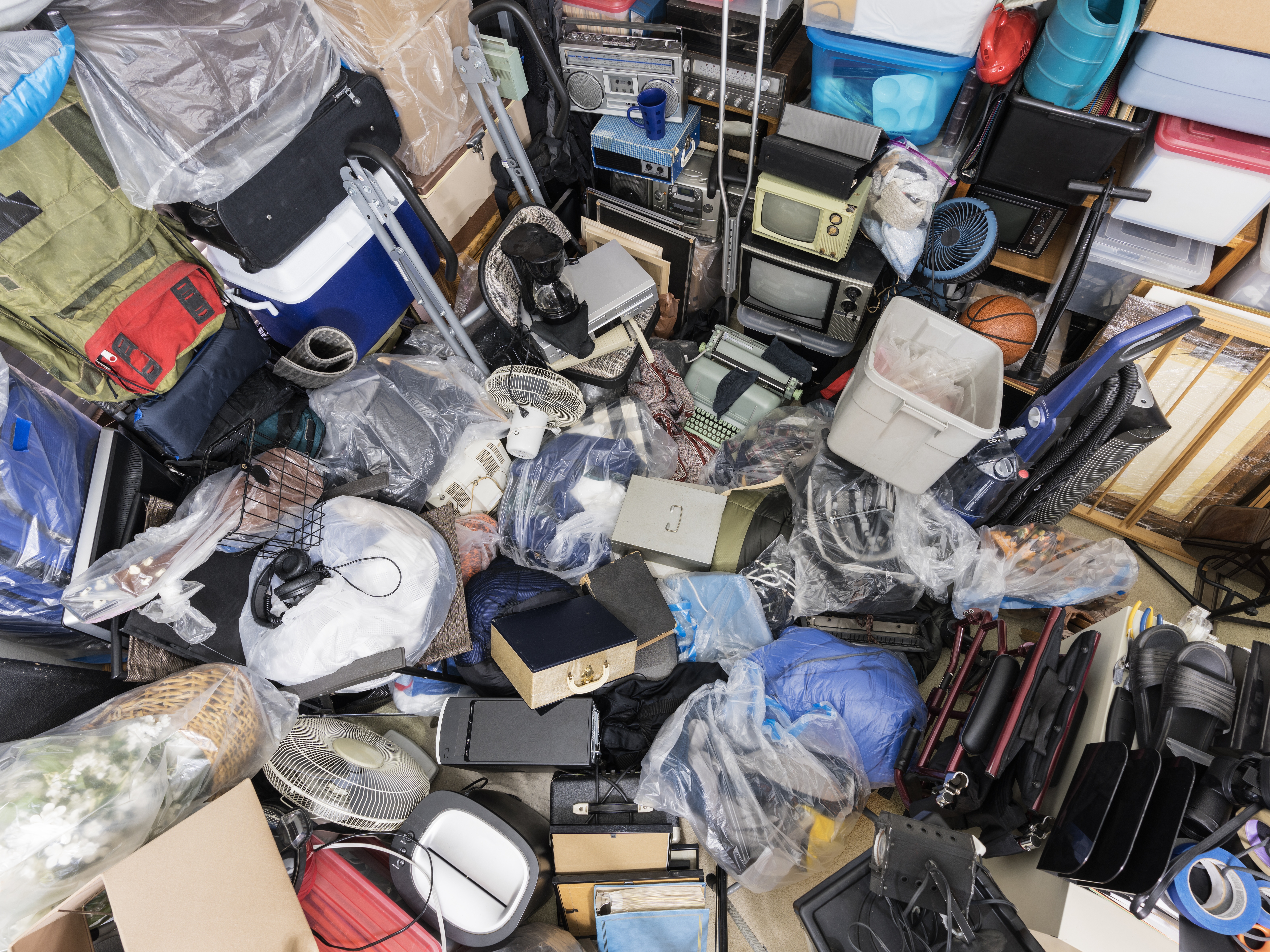 Pile of objects accumulated in someone's home including clothing and outdoor equipment, household objects, and old electronics.