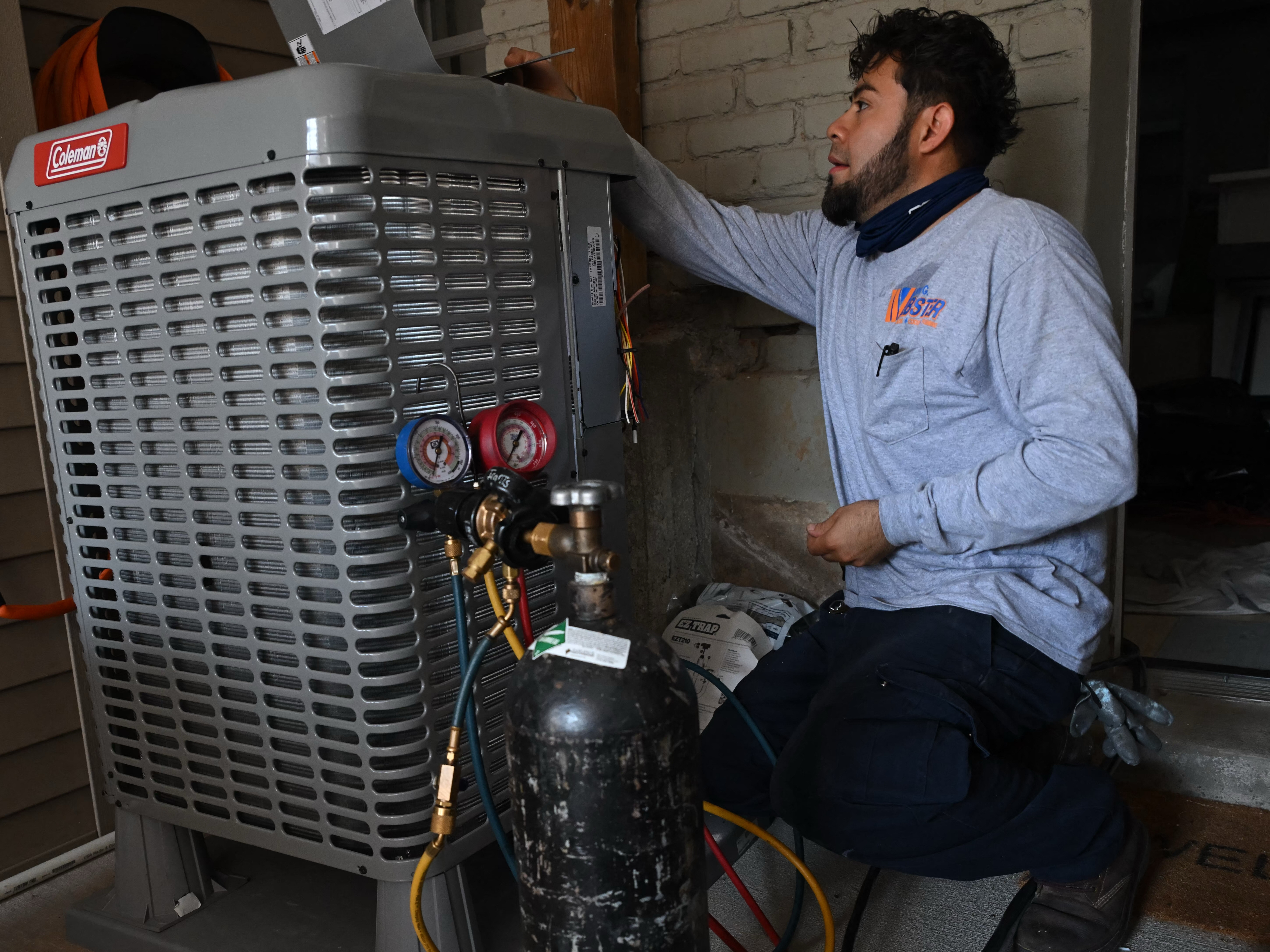 A technician installs an electrical heat pump at a home in Washington, DC, in August 2024.